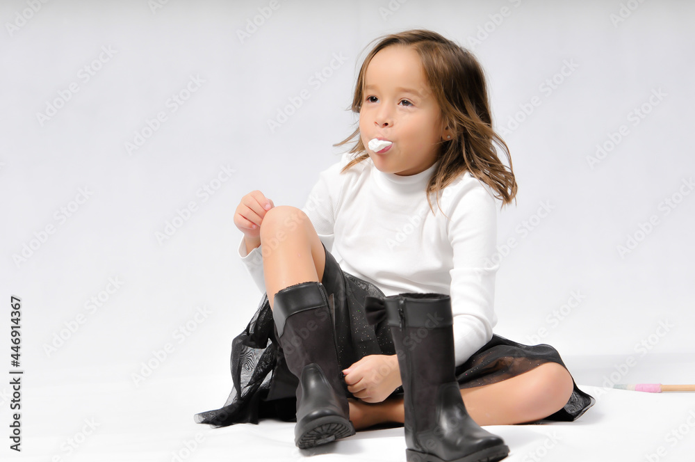 Portrait of happy pretty curly little girl sit on the floor and playing toy stick over white background , play and fun conceptual Portrait of happy pretty curly little girl sit on the floor and playing toy stick over white background , play and fun conceptual