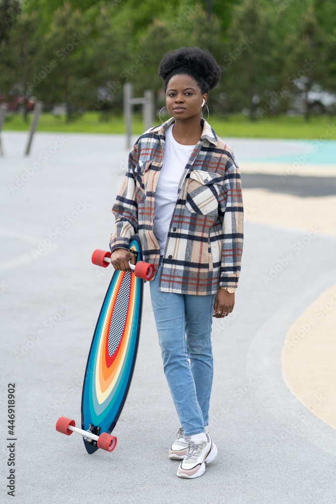 Young african american girl skateboarder hold longboard in skate park.  Modern urban female in casual street style clothes in city skatepark with  skateboard training longboarding. Hipster hobby concept Stock Photo | Adobe