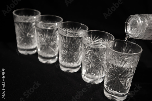 glasses in which vodka is poured on a black background
