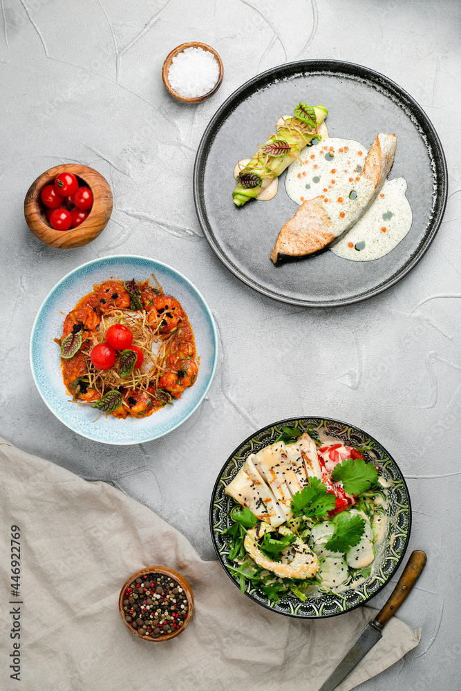 table full of seafood. salmon steak grilled shrimp and squid salad with avocado top view, seafood table concept