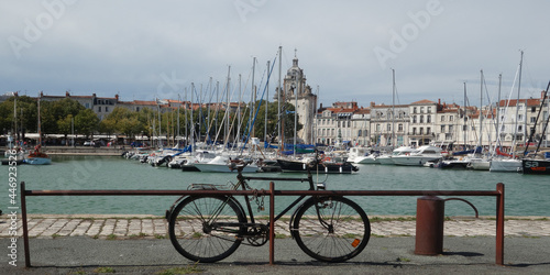 a bicycle in the harbor with yachts in front of the old town and the clock tower, La Rochelle, Bay of Biscay, France
