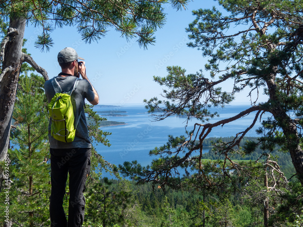 Man taking picture of view of the ocean with islands and blue sky
