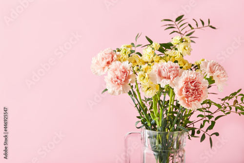 Bouquet of pink carnations and yellow matthiola with green branches. Design concept of holiday greeting with carnation bouquet on pink background