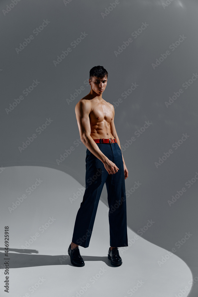 a man with a pumped-up torso in jeans and boots stands in full growth a man with a pumped-up torso in jeans and boots stands in full growth