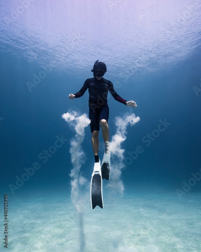 Person freediving in the ocean, playing with sand photo