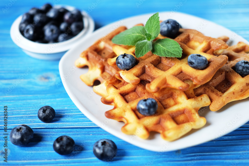 Traditional belgian waffles with fresh berrys and sugar powder on white plate, blue wooden background. Traditional belgian waffles with fresh berrys and sugar powder on white plate, blue wooden background.