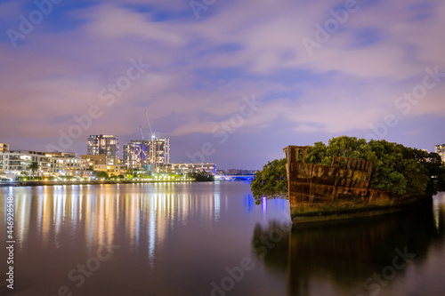 Shipwreck on river with cityscape long exposure photo