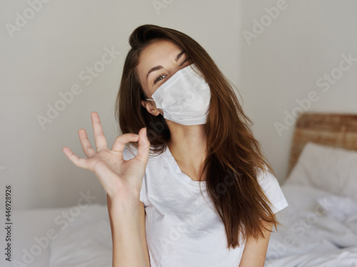 woman wearing medical mask positive hand gesture sleeping room