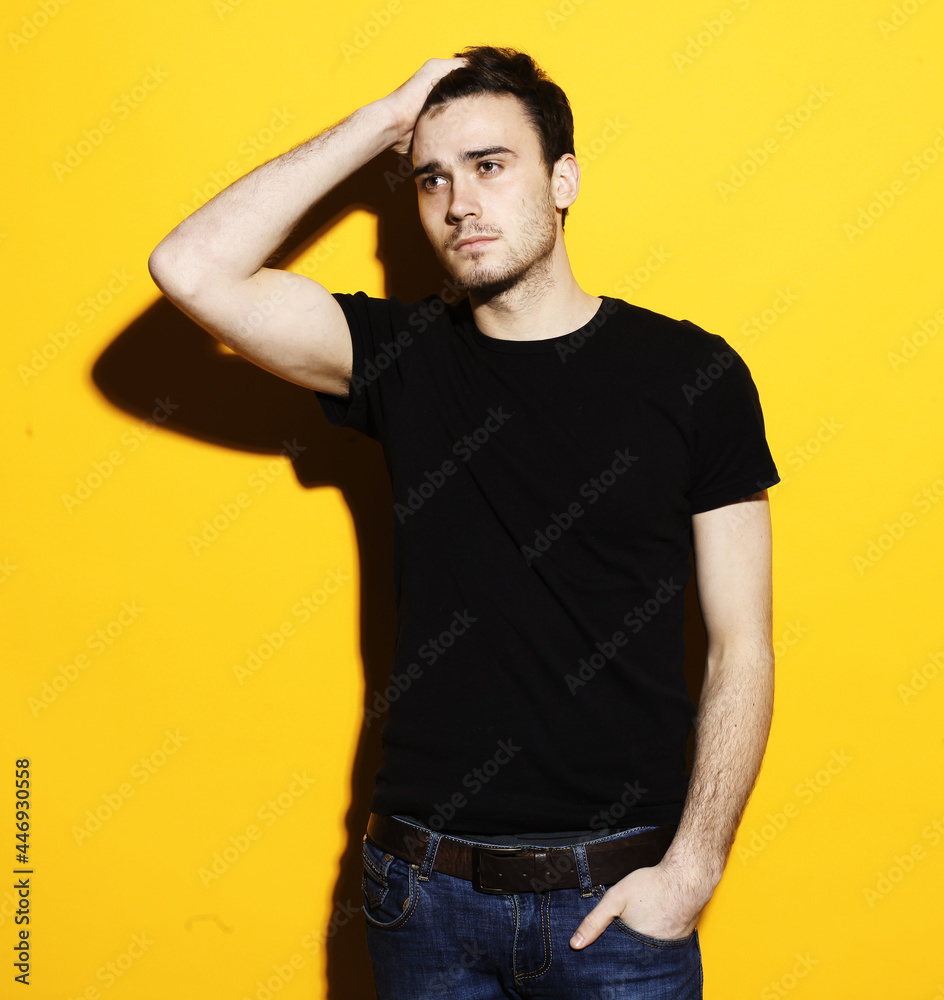 Young handsome male model standing against yellow background