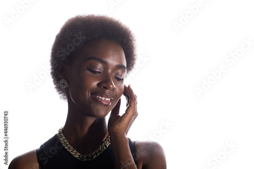 Close up portrait of smiling african american woman with closed eyes touching face on white studio background.
