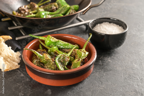 Fried peppers de padron or green pimientos in a traditional Spanish tapa bowl on a dark gray slate background, copy space, selected focus photo