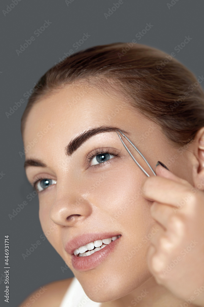Tweezing eyebrows. Eyebrow correction. Plucking eyebrows. Beautiful young woman with tweezers. Model with beauty Face. .Tweezing eyebrows. Tweezing eyebrows. Eyebrow correction. Plucking eyebrows. Beautiful young woman with tweezers. Model with beauty Face. .Tweezing eyebrows.