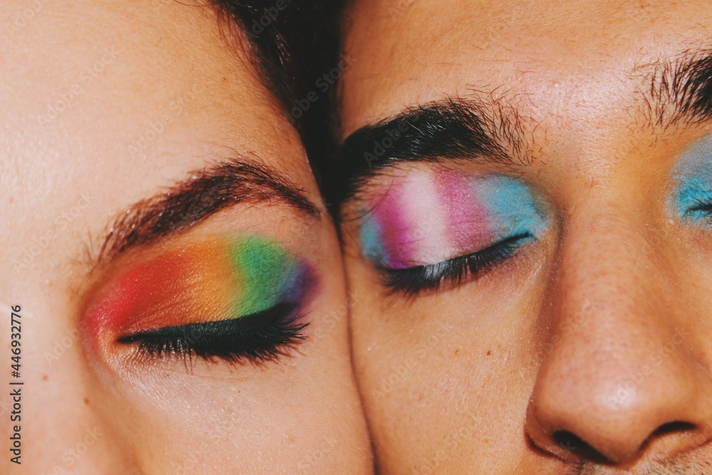 Closeup portrait of queer friends / young couple faces & eyes wearing eyeshadow makeup of lgbtq rainbow pride flag & trans pride flag - obrazy, fototapety, plakaty 