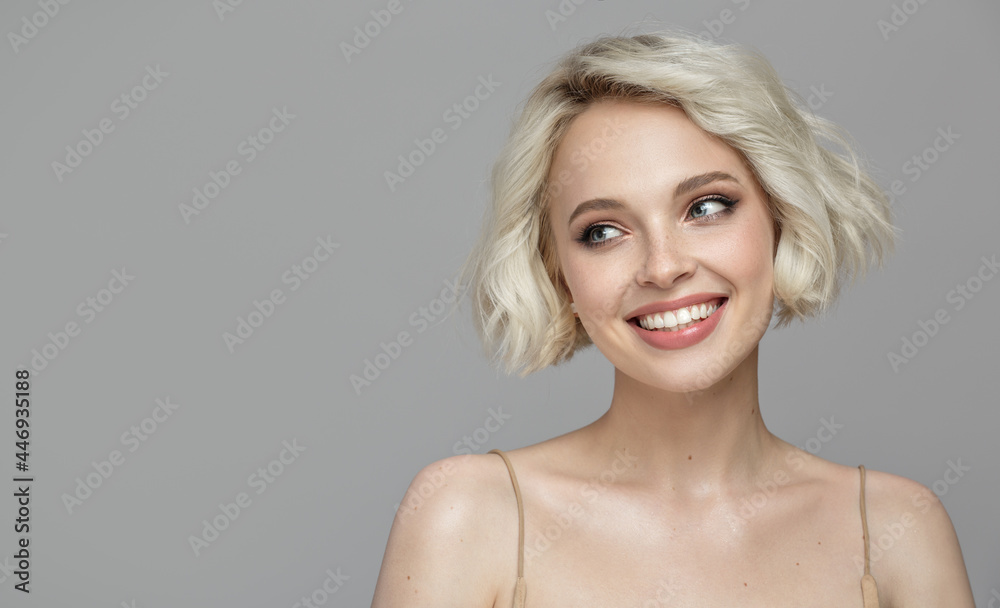 Portrait of a beautiful smiling blonde girl with a short haircut. Gray background. Portrait of a beautiful smiling blonde girl with a short haircut. Gray background.