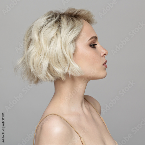 Portrait of a beautiful blonde girl with a short haircut. Gray background. photo