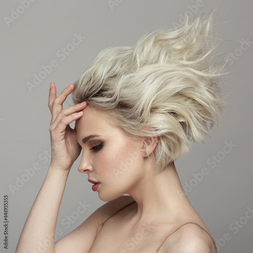 Portrait of a beautiful blonde girl with a short haircut. Gray background.