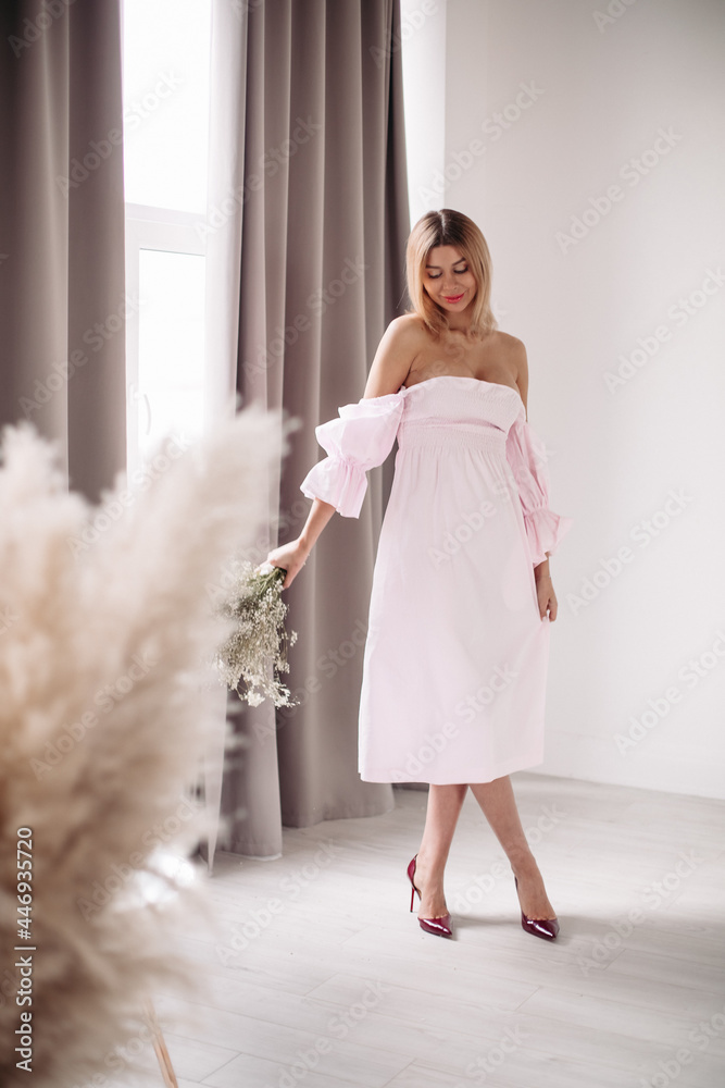 beautiful woman in white dress standing near the big window with a lot of shine beautiful woman in white dress standing near the big window with a lot of shine