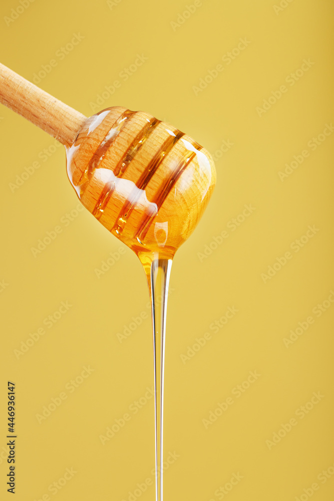 Natural Honey flows down from a honey bucket on a yellow background. Natural Honey flows down from a honey bucket on a yellow background.