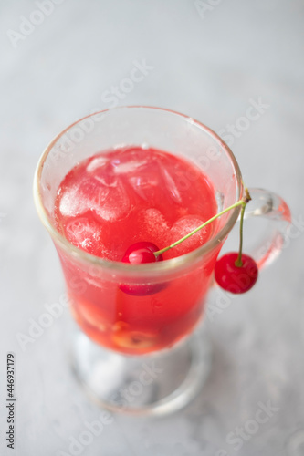 Fresh cherry fruit juice compote in a glass with ice  in the shape of a heart on a light background