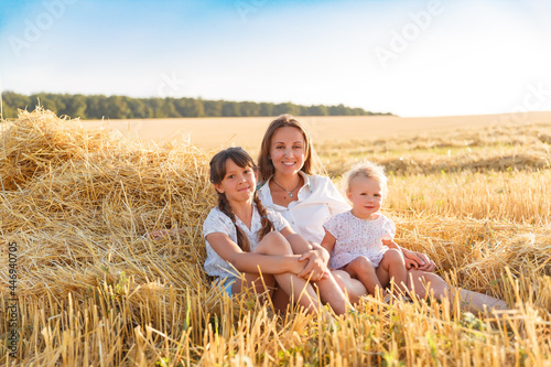 Mother and daughters walk in the wheat field 