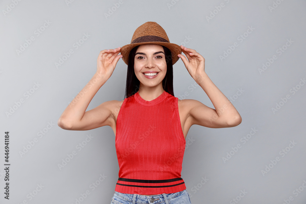 Beautiful young woman with straw hat on light grey background Beautiful young woman with straw hat on light grey background