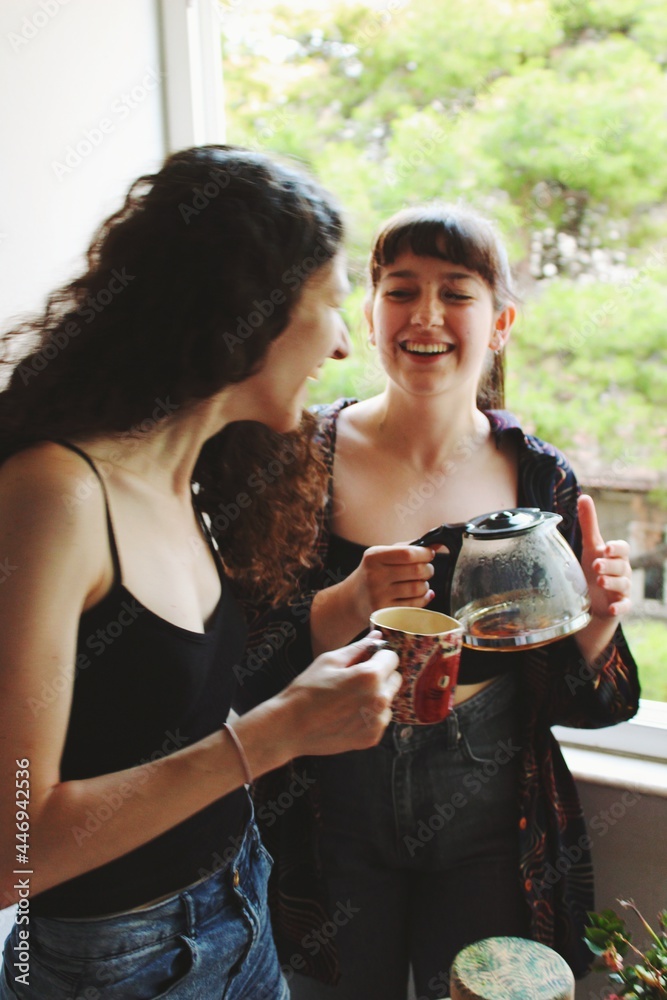 smiling happy portrait of two women / lesbian couple at home smiling & drinking coffee