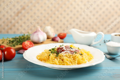 Tasty spaghetti squash with tomato sauce, cheese and thyme served on light blue wooden table