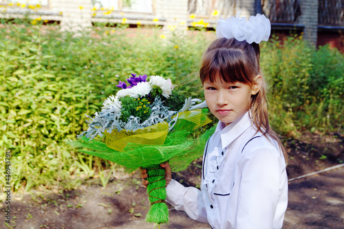 A girl with a bouquet of flowers and a briefcase goes on September 1 photo