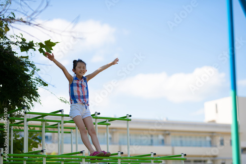 校庭のジャングルジムで遊ぶ少女