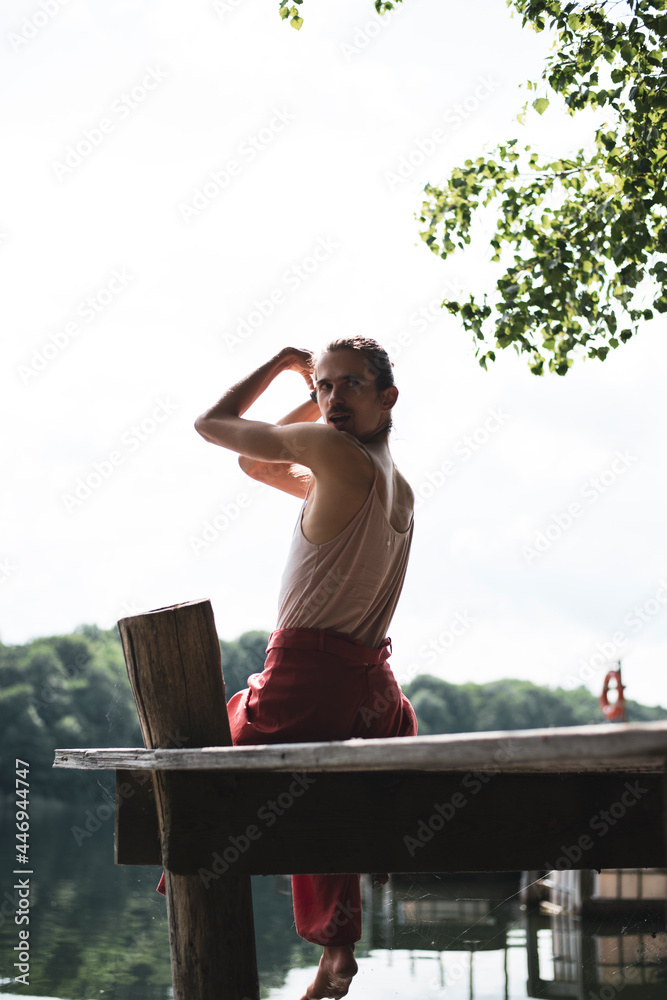 non-binary person plays with hair on edge of lake jetty in poland non-binary person plays with hair on edge of lake jetty in poland