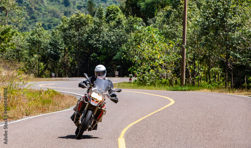 Man riding his adventure motorbike on windy road in Cambodia Man riding his adventure motorbike on windy road in Cambodia