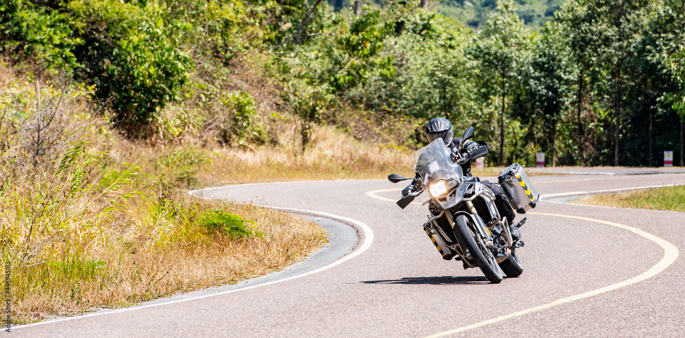 Man riding his adventure motorbike on windy road in Cambodia Man riding his adventure motorbike on windy road in Cambodia