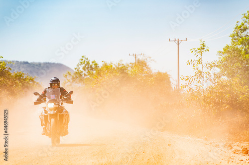 Man riding his adventure motorbike on dusty road in Cambodia