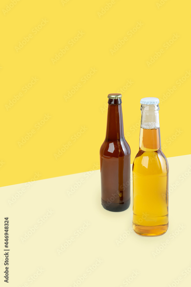A bottles of craft lager and porter beer on dual color yellow background. International beer day or Octoberfest concepts. Minimalistic colors on a photo.Copy space. isometric diagonal projection A bottles of craft lager and porter beer on dual color yellow background. International beer day or Octoberfest concepts. Minimalistic colors on a photo.Copy space. isometric diagonal projection