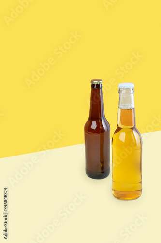 A bottles of craft lager and porter beer on dual color yellow background. International beer day or Octoberfest concepts. Minimalistic colors on a photo.Copy space. isometric diagonal projection