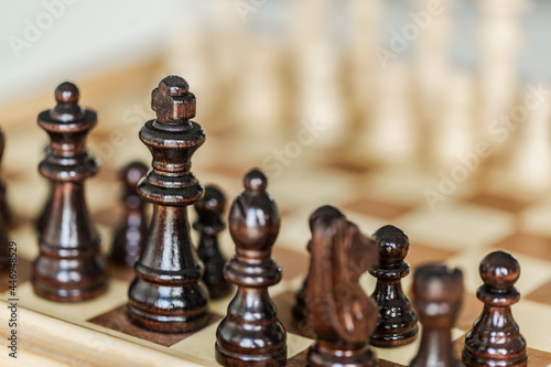 Wooden chess pieces set up on board game indoors photo