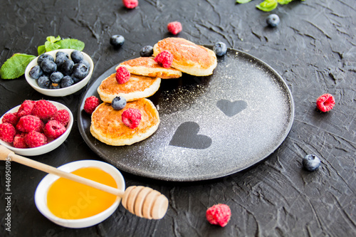 A healthy breakfast of cheese pancakes, berries, and honey. Creative atmospheric decoration
