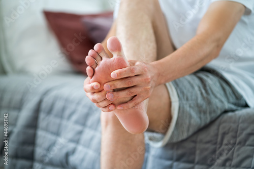 Foot pain  man suffering from feet ache in home interior