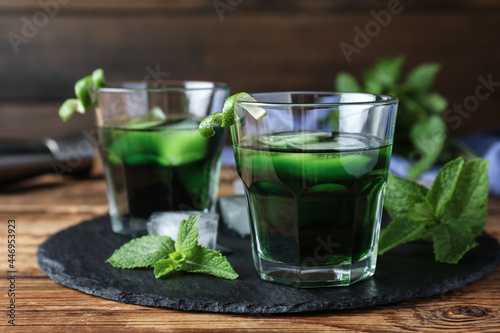 Delicious mint liqueur with green leaves on wooden table