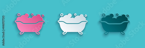 Paper cut Bathtub with foam bubbles inside icon isolated on blue background. Paper art style. Vector