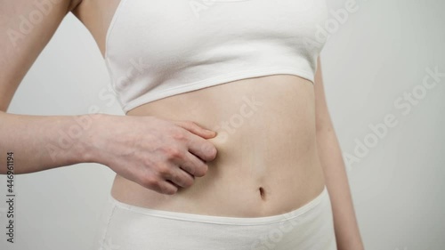 Wallpaper Mural A plump woman pinches her belly. Overweight and weight loss concept. Close-up, isolated on white, 4K UHD. Torontodigital.ca