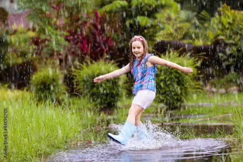 Kid with umbrella playing in summer rain.