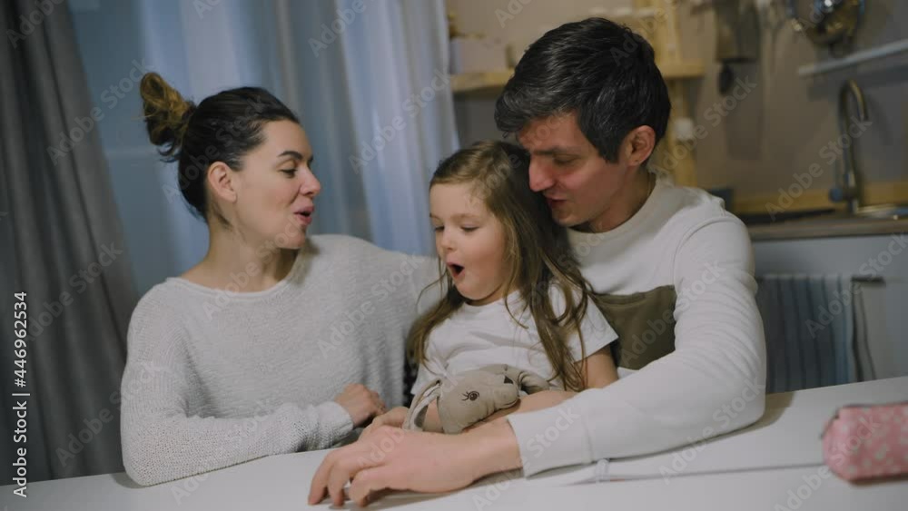 Happy caucasian family mom dad and little daughter sing a song in the kitchen. Happy caucasian family mom dad and little daughter sing a song in the kitchen.