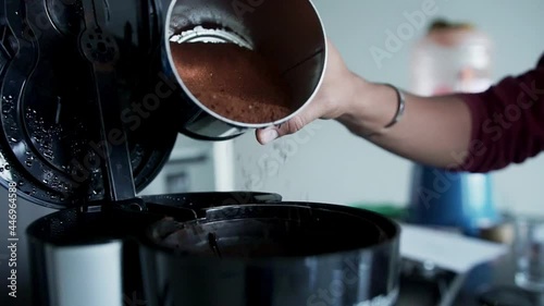hand drops coffee on a coffee pot
