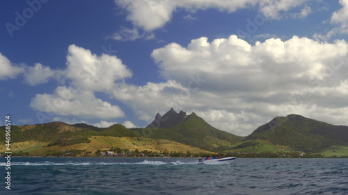 Waterside view of green Mauritius Island with mountains