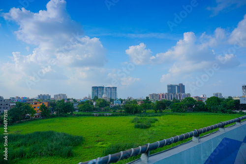 Kolkata cityscape , old and modern architecture of buildings, blue sky and white clouds in background with green field foreground.