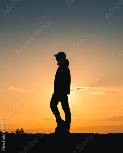 Fototapeta Naklejka Na Ścianę i Meble -  silhouette of an tourist man at sunset with orange sky in the top view of mountain