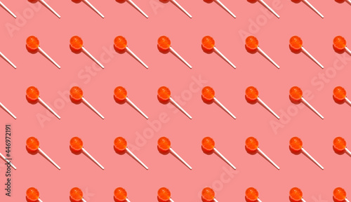 Seamless pattern of ball lollipops on stick above a pink background. Festive background for holiday paper.