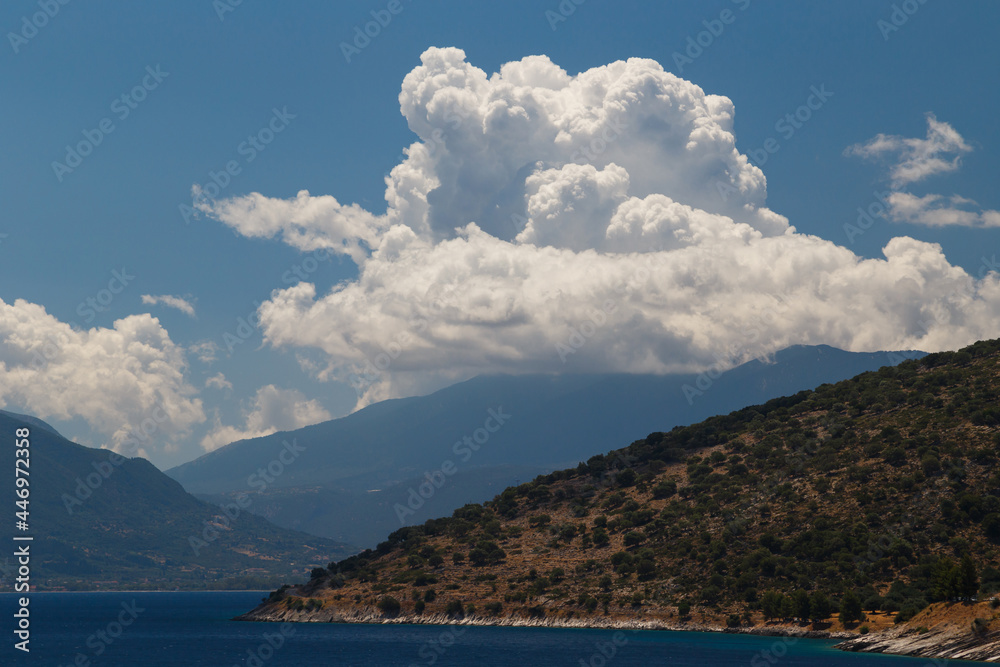 A fantastic view at Cephalonia island, famous and extremely popular travel destination in Greece, Europe. Blue Ionian sea water, hills and beautiful cumulus clouds.