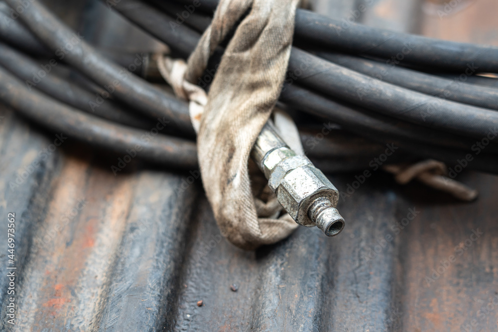 A part of hydraulic flexible hose for high pressure using. Industrial equipment and object photo. Close-up and selective focus at the connection joint. A part of hydraulic flexible hose for high pressure using. Industrial equipment and object photo. Close-up and selective focus at the connection joint.
